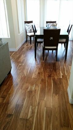 a dining room table and chairs with wood flooring in front of the window,