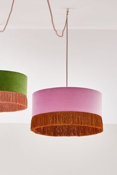 two lamps hanging from the ceiling with different shades of pink, green and orange on them