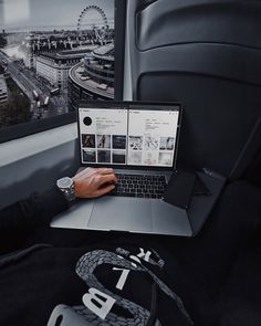 a person using a laptop in the back seat of a car with a city view behind them