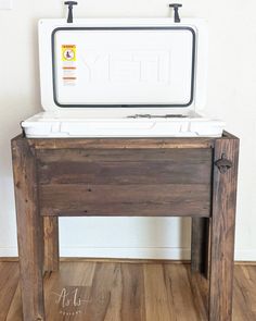 an ice chest sitting on top of a wooden table next to a white wall and wood floor