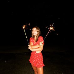 a girl in a red dress holding two sparklers