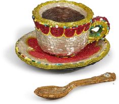 a cup and saucer made out of beads with a wooden spoon on the side