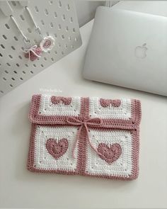 a laptop computer sitting on top of a desk next to a crocheted coaster