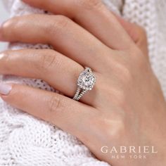 a woman's hand with a diamond ring on her finger and a white sweater