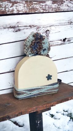 a hat on top of a wooden bench with snow in the backgroung