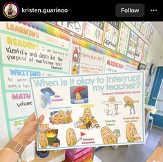 a person holding up a poster in front of a classroom wall with writing on it