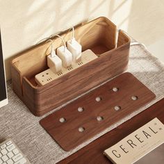 a desk with a keyboard, mouse and two plugs in a wooden box on it