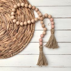 a wooden beaded necklace with tassels on a woven basket next to it