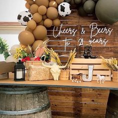 a table topped with lots of balloons next to a wooden barrel filled with hay and other items