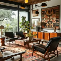 a living room filled with lots of furniture and large windows overlooking the trees in the distance