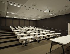 an empty room with rows of white tables and benches in the center, along with carpeted flooring