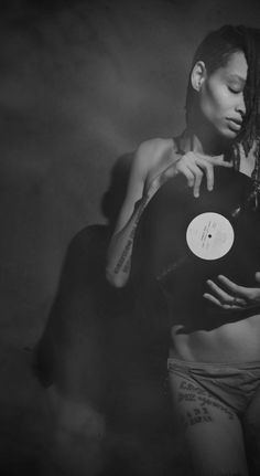 a black and white photo of a woman with dreadlocks holding a frisbee