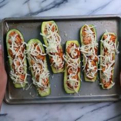 four stuffed zucchini boats on a baking sheet with parmesan cheese and sauce