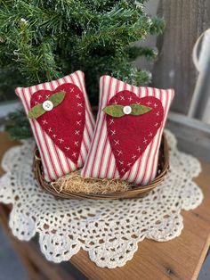 two red hearts are sitting in a basket on a doily next to a tree