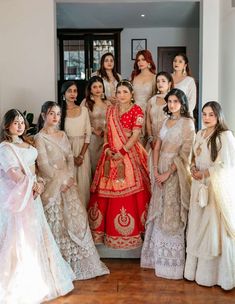 a group of women standing next to each other in front of a doorway wearing white and red outfits