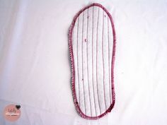 a piece of cloth is laying on top of a white sheet with pink thread and beads