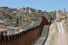 a dirt road next to a large fence