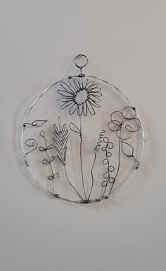 a glass plate with flowers on it hanging from the ceiling in front of a white wall