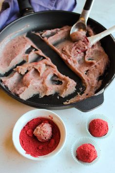 a pan filled with red food next to two bowls