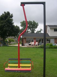 a park bench sitting on top of a green grass covered field in front of a house