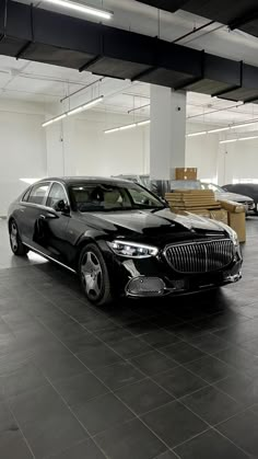 a black car is parked in the middle of an empty room with boxes on the floor