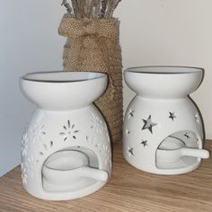 two white vases sitting on top of a wooden table