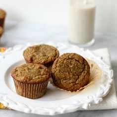 three muffins on a white plate with a glass of milk in the background