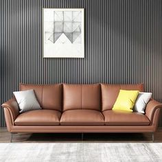 a brown leather couch sitting in front of a painting on the wall next to a lamp