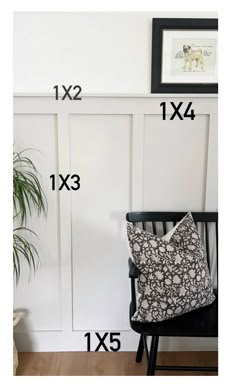 a black chair sitting in front of a white wall with measurements for the pillow on it