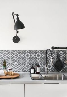 a kitchen with a sink, faucet and wall lamp