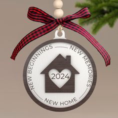 a wooden ornament with a house and heart on it hanging from a christmas tree