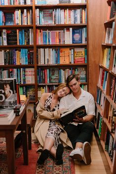 a man and woman sitting in front of a bookshelf