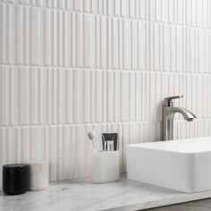 a white sink sitting on top of a counter next to a toothbrush dispenser