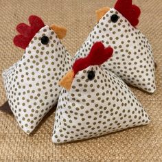 two white and red chickens sitting on top of a brown cloth covered floor next to each other