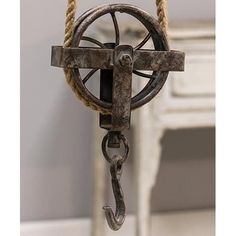 an old metal pulley with rope hanging from it's side in front of a white dresser