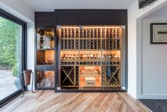 a wine cellar in the corner of a room with wood flooring and glass doors