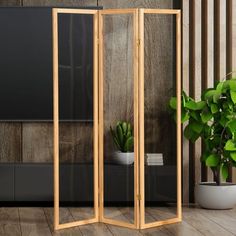 a room divider made out of wood and glass in front of a potted plant