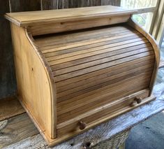 a wooden mailbox sitting on top of a piece of wood next to a window