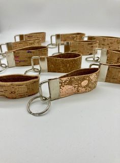 several cork bracelets with metal clasps on a white surface, one is open and the other is closed