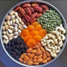 an assortment of nuts and dried fruits in a metal bowl