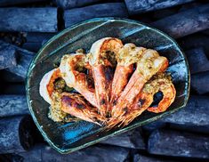 cooked shrimp and rice in a glass dish on top of firewood logs, viewed from above