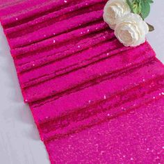 pink sequin table runner with white flowers on top