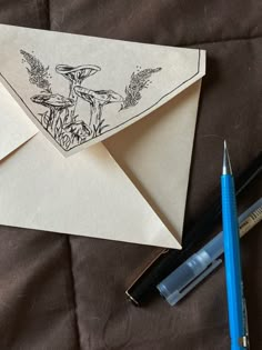 an envelope with a drawing on it next to some pens