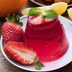 there is a strawberry jelly on the plate with some sliced strawberries and lemons in the background