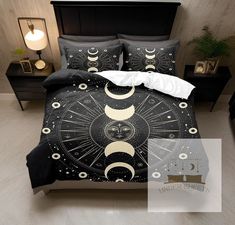 a bed covered in black and white comforter with an image of the moon on it