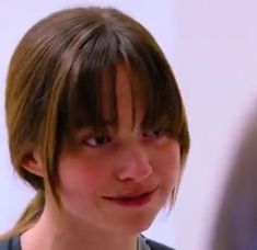 a close up of a person wearing a shirt and smiling at the camera with a blurry background