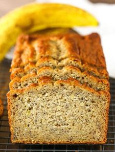 a loaf of banana bread sitting on top of a cooling rack next to two bananas