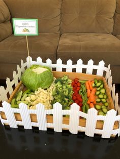 a wooden box filled with vegetables on top of a table next to a brown couch