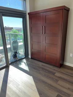 an empty room with wooden floors and large sliding glass doors that lead to a balcony