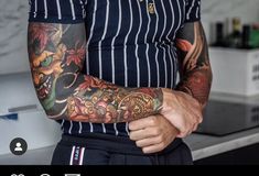 a man with tattoos on his arm standing in a kitchen